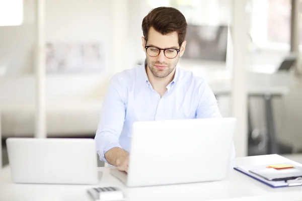 Uomo seduto in ufficio davanti ai computer portatili — Foto Stock