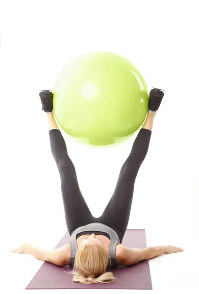 Mujer levantando una pelota de ejercicio — Foto de Stock