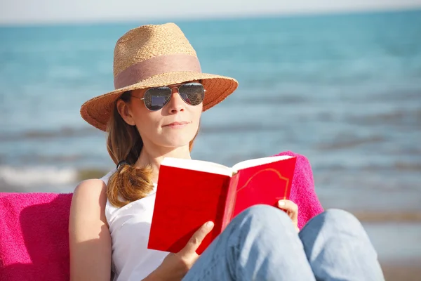 Mujer relajándose en la playa y leyendo — Foto de Stock