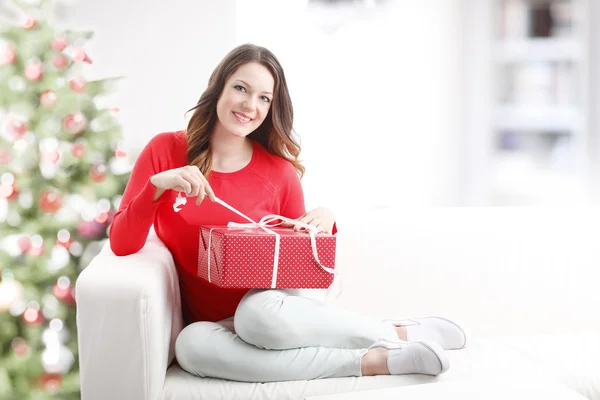 Frau sitzt zu Hause und öffnet Geschenk — Stockfoto