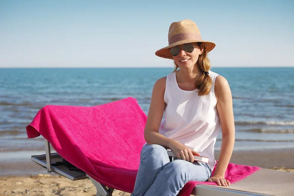 Kumlu plajda şezlong üzerinde oturan kadın — Stok fotoğraf