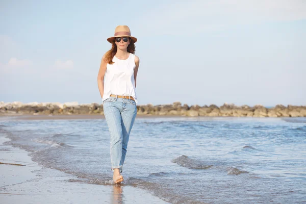 Kumlu bir plaj boyunca yürüyen kadın — Stok fotoğraf