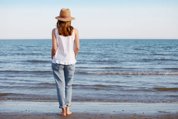 Mujer relajada caminando a lo largo de una playa de arena — Foto de Stock