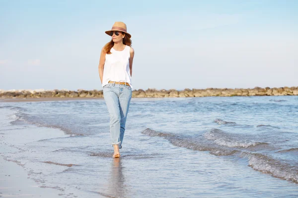 Зрелая женщина, идущая вдоль пляжа — стоковое фото