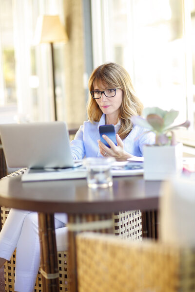 woman with mobile and laptop sitting