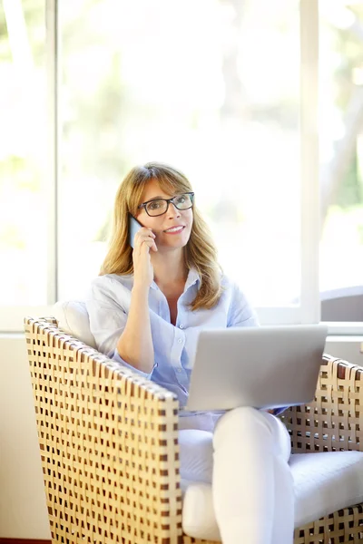 Kvinna med mobil och laptop sitter — Stockfoto