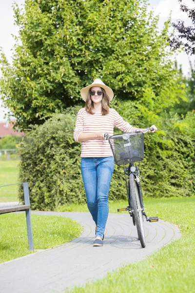 Donna con la sua bicicletta a piedi — Foto Stock