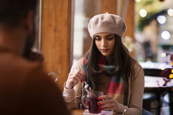 カフェでテーブルに座ってお茶を飲みながら帽子とスカーフを被った美しい女性の肖像画 — ストック写真