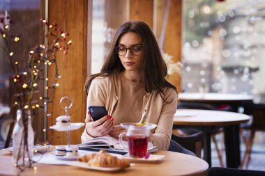 Kafede masada oturan kendine güvenen bir kadın ve kısa mesaj.. 