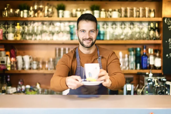 Strzał Uśmiechniętego Kelnera Stojącego Ladą Trzymającego Filiżankę Herbaty Ręce — Zdjęcie stockowe