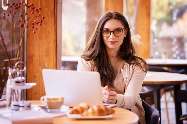 穿着时髦休闲装的自信的年轻女人坐在咖啡店的窗边 用她的笔记本电脑 — 图库照片
