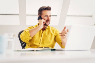 Kendine güvenen bir iş adamının laptopunun arkasında oturup evden telefon açarken görüntüsü. Merkez Ofis.