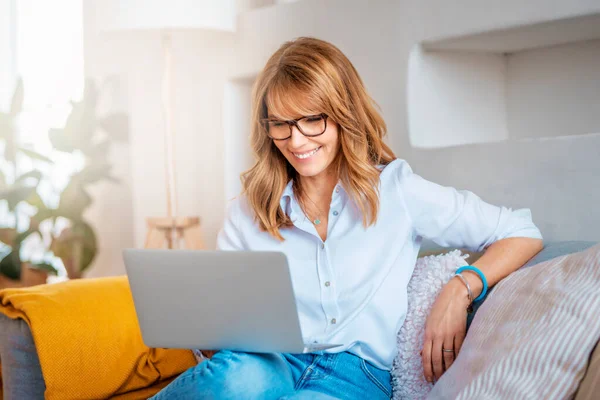 Tiro Uma Mulher Meia Idade Usando Laptop Sofá Casa Empresária — Fotografia de Stock