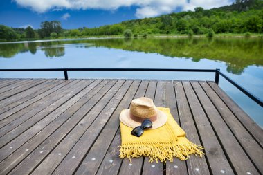 Göl kıyısında yüksek açılı hasır şapka ve güneş gözlüğü. Yaz tatili kavramı. Canlı renkler.