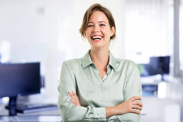 Atrakcyjna Bizneswoman Patrząc Obiektyw Śmiejąc Się Stojąc Rękami Skrzyżowanymi Biurze — Zdjęcie stockowe