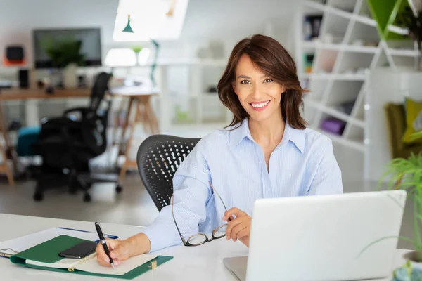 Glückliche Geschäftsfrau Sitzt Schreibtisch Hinter Ihrem Laptop Und Schreibt Während — Stockfoto