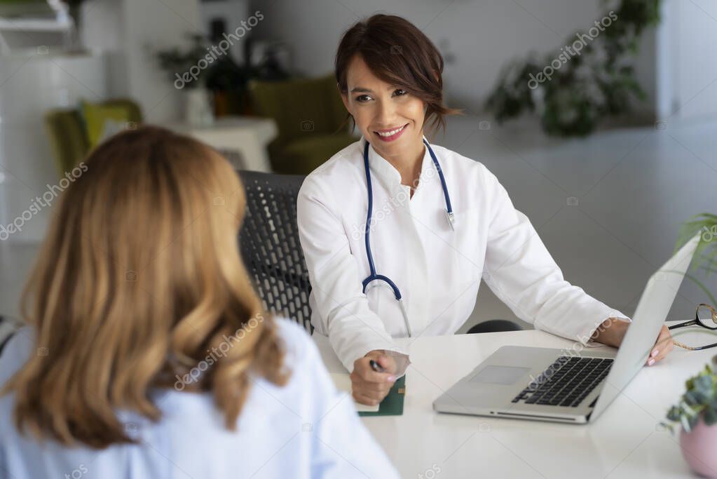 Doctora que trabaja en el consultorio y escucha a la paciente mientras