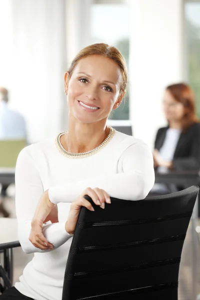 Зріла бізнес-леді сидить в офісі — стокове фото