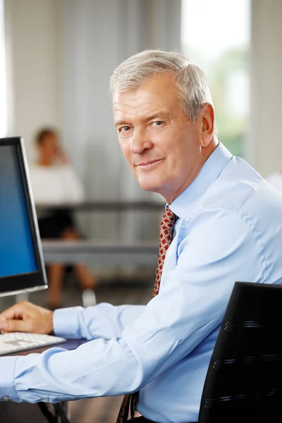 Old businessman sitting at office — Stock Photo, Image