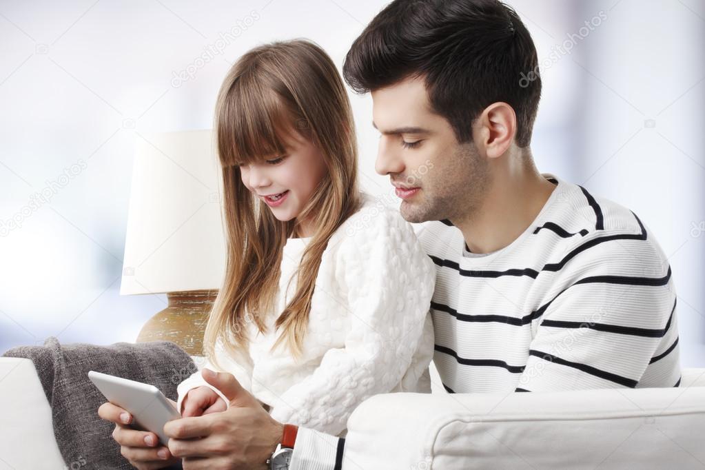 Girl with dad using tablet.