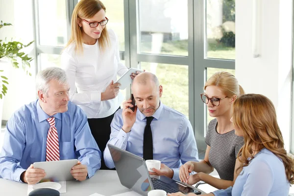 Businesswomen and businessmen sitting at desk — Stock Photo, Image