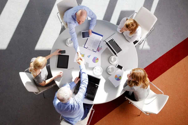 Företag som sitter runt skrivbord — Stockfoto