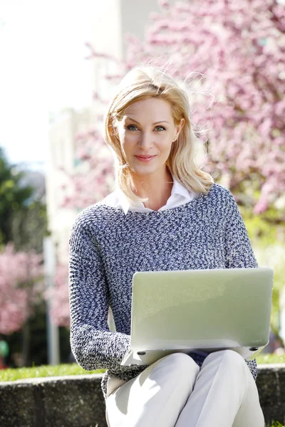 Forretningskvinde sidder på udendørs med laptop - Stock-foto