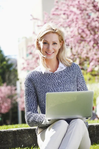 Affärskvinna sitter på utomhus med laptop — Stockfoto