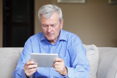 man sitting at sofa with tablet