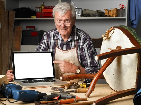 Carpenter points out of laptop — Stockfoto