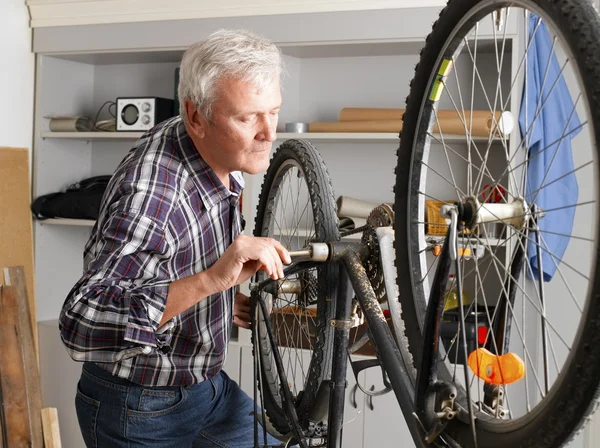 Retired bicycle mechanic standing in workshop — Stock Photo, Image