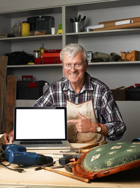 Carpenter points out of laptop screen — Stockfoto
