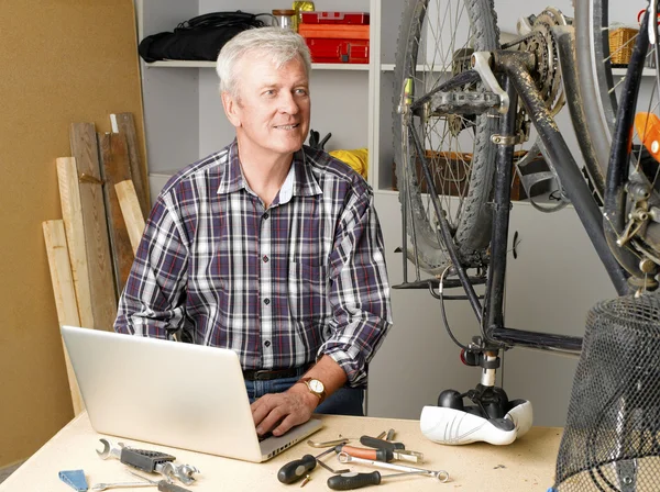 Hombre sentado en el taller de reparación de bicicletas — Foto de Stock