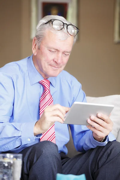 Vanhempi mies istuu tilalla tabletti — kuvapankkivalokuva