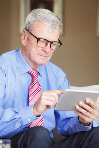 Senior man sitting holding tablet — Stockfoto