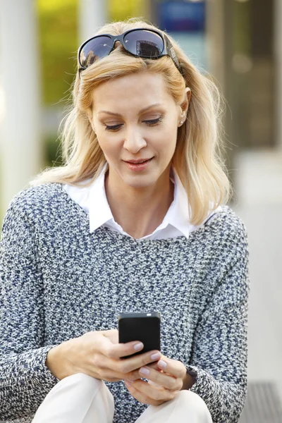 Mujer sentada al aire libre y usando móvil — Foto de Stock