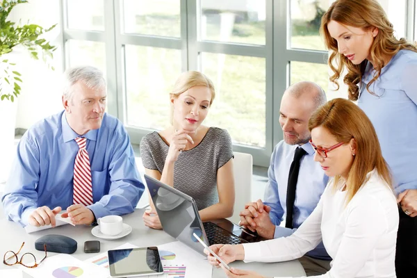 Businesswomen and businessmen around conference table — Stock Photo, Image