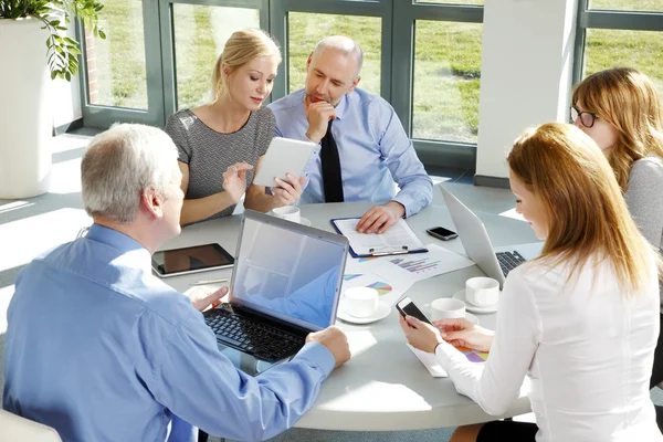 Businesswomen and businessmen around conference table — Stock Photo, Image