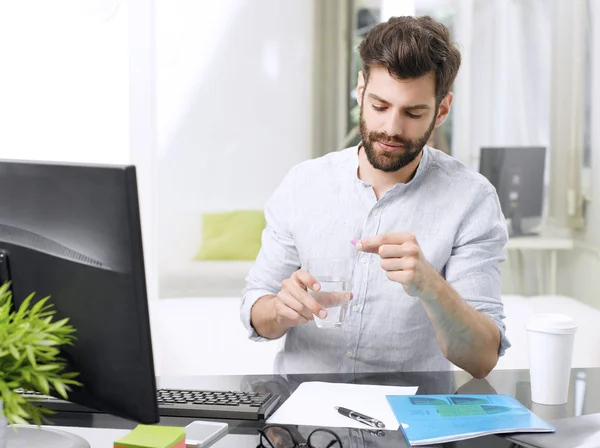 Businessman at office and takes medicine — Stock Photo, Image