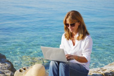 smiling woman by see using computer