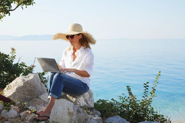 Woman by the see and using her personal computer — Stockfoto