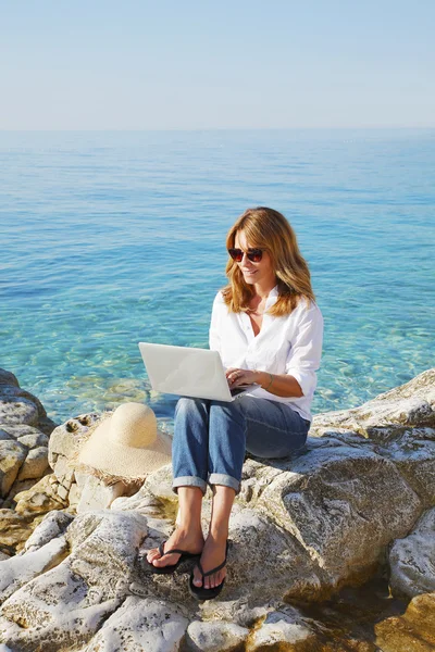Woman by the see and using her personal computer — Φωτογραφία Αρχείου