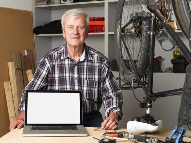 senior bike shop owner with laptop