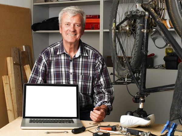 Senior bike shop owner behind laptop — Zdjęcie stockowe