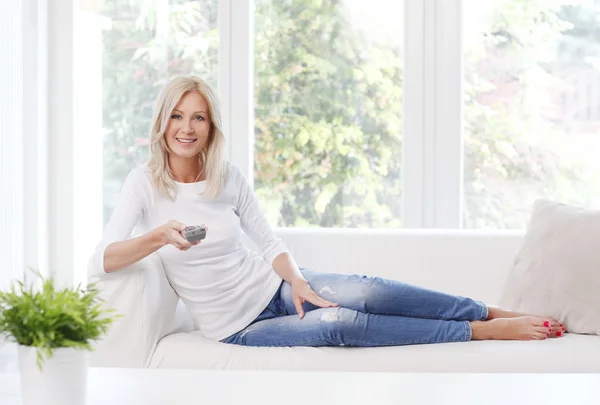 Mujer sonriendo mientras está sentada en casa —  Fotos de Stock