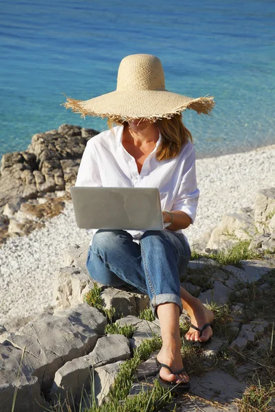 Kobieta z laptopa siedząc na plaży — Zdjęcie stockowe