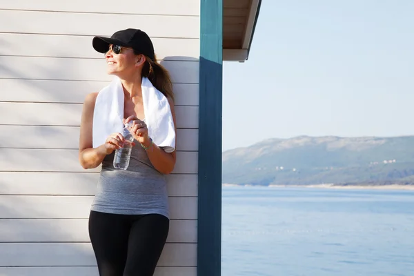 Sporty woman standing by sea — Stock Photo, Image