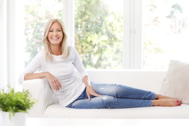 Olgun kadın kanepe otururken gülümseyen