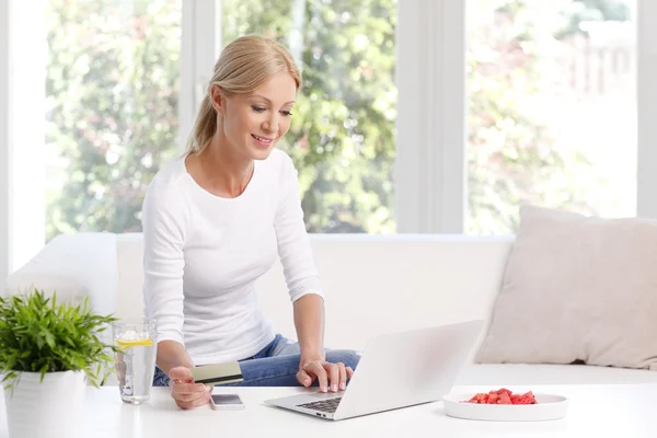 Femme assise sur le canapé devant un ordinateur portable — Photo