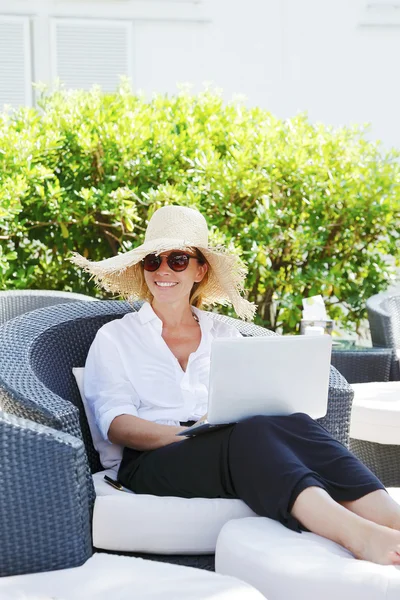 Kvinna sitter på garden med laptop — Stockfoto